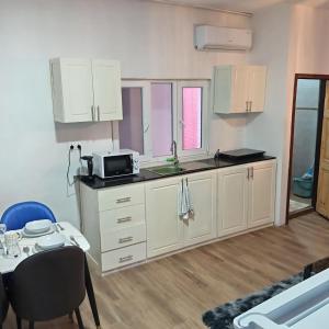a kitchen with white cabinets and a table in a room at Comfort Corner in Amdalai