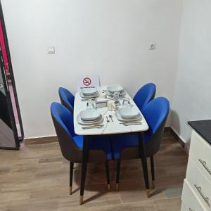 a table with blue chairs and plates on it at Comfort Corner in Amdalai