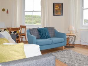 a living room with a blue couch and a table at Church St 1 Upper Apartment - Cottage in Salcombe