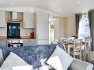 a living room with a blue couch and a kitchen at Lodge 10 Bridlington Holiday Park - Uk48212 in Carnaby