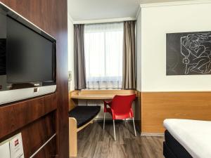 a hotel room with a desk and a tv at ibis Hotel Eisenach in Eisenach