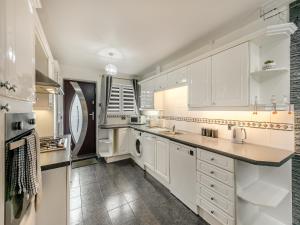 a kitchen with white cabinets and a washer and dryer at Cherrytrees in Scarborough +16 photos