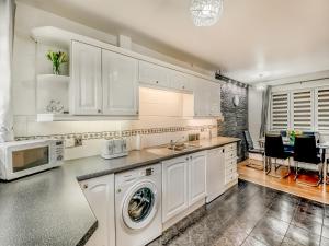 a kitchen with white cabinets and a washer at Cherrytrees in Scarborough