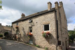 ein altes Steinhaus mit Blumen am Straßenrand in der Unterkunft Ramblers Rest in Castleton
