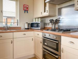 a kitchen with white cabinets and a stove top oven at Grandma's Stick House in West Down