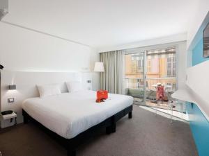 a bedroom with a bed with a red bag on it at Ibis Styles Menton Centre in Menton