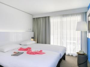 a hotel room with a bed with pink clothes on it at Ibis Styles Menton Centre in Menton +167 photos