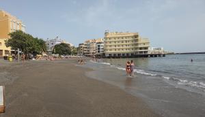 Un par de personas caminando por la playa en Casa Claudia 1 Primero Derecha, en Granadilla de Abona
