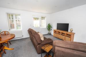 a living room with a couch and a television at Modern 2-Bed Home with Driveway – Basingstoke in Sherborne Saint John