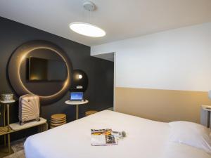 a bedroom with a bed and a round mirror at ibis Styles Pertuis Portes du Luberon in Pertuis