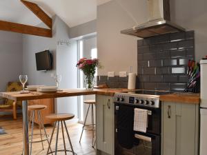 a kitchen with a stove and a counter with stools at Owl Cottage in Ryton