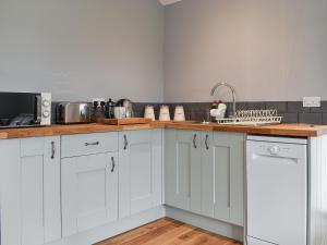 a kitchen with white cabinets and a sink at Owl Cottage in Ryton