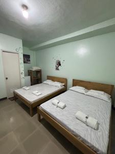 two twin beds in a room with two towels on them at Mischa Hostel in Dauis