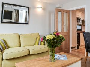 a living room with a couch and a vase of flowers on a table at Chapel Mouse Cottage in Cockermouth