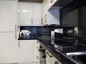 a kitchen with white cabinets and black counter tops at 7 Oaklands in Ambleside