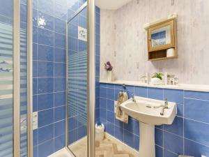 ein blau gefliestes Bad mit einem Waschbecken und einer Dusche in der Unterkunft Carraig Dhubh Cottage - Uk47123 in Whiting Bay