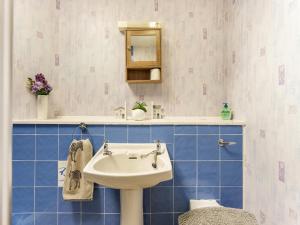 ein Badezimmer mit weißem Waschbecken und blauen Fliesen in der Unterkunft Carraig Dhubh Cottage - Uk47123 in Whiting Bay + 4 Fotos