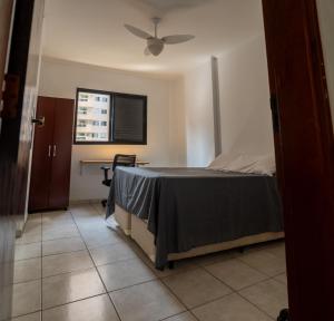 a bedroom with a bed with a ceiling fan at Apartamento completo com garagem a 150 m da praia in Praia Grande