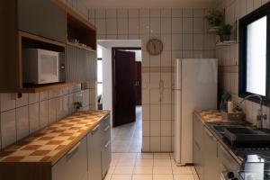 a kitchen with a refrigerator and a tile floor at Apartamento completo com garagem a 150 m da praia in Praia Grande