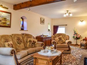 Una sala de estar con sofás y una mesa. en Priory Barn, en Burscough