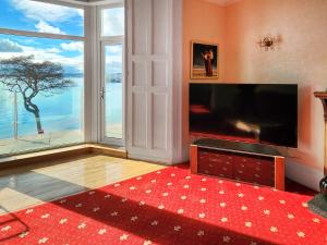 a living room with a large television and a large window at Riviera Mansion, Torquay in Torquay