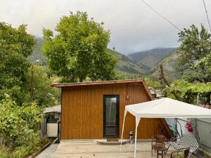 une petite maison avec une tente et des chaises blanches dans l'établissement Buddy Apartment Borjomi, à Bordjomi