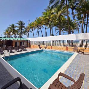 einen Pool mit 2 Stühlen und Palmen in der Unterkunft Tucacas, Frente al Mar, Vista a la Piscina y Playa Privada in Boca de Aroa