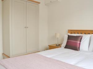 1 dormitorio con 1 cama blanca y armario en High Brow, en Bowness-on-Windermere