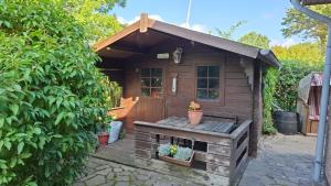 a small wooden shed with a bench in a garden at Großes Ferienhaus Dagebüll mit Kamin in Dagebüll