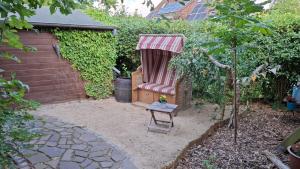 Un jardín con una silla roja con dosel. en Großes Ferienhaus Dagebüll mit Kamin, en Dagebüll