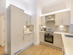 a white kitchen with white cabinets and a stove at Weaver's Snug in Haworth