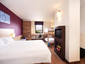 Una habitación de hotel con una cama y un televisor. en Ibis Bangkok Riverside, en Bangkok