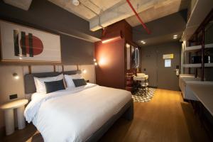 Un dormitorio con una gran cama blanca y un escritorio. en Tribe Medellín, en Medellín