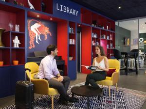 a man and woman sitting in chairs in a library at Aparthotel Adagio Basel City in Basel