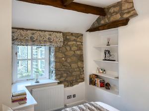 a bedroom with a stone wall and a window at Candy Cottage in Addingham