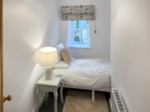 a small bedroom with a bed and a table with a lamp at Candy Cottage in Addingham +2 photos