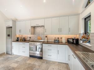 a kitchen with white cabinets and a stove top oven at Foxton Lodge - Uk47296 in Harrietsham