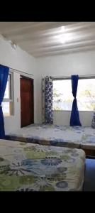 a bedroom with two beds and a window with blue curtains at Uncle Bob&Tere's Beachfront House in Luna +3 photos