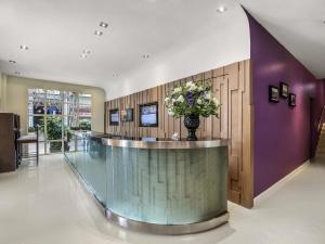 a lobby with a reception counter with a vase of flowers at Mercure Hanoi La Gare Hotel in Hanoi +103 photos