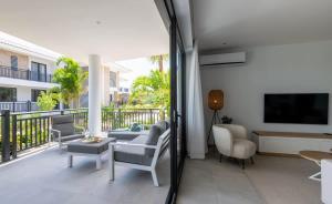 ein Wohnzimmer mit Couch und Fernseher auf einem Balkon in der Unterkunft Summer Breeze in Blue Bay + 25 Fotos