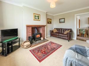 Una sala de estar con chimenea y un sofá. en Kilquhanity Cottage, en Castle Douglas