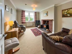 Una sala de estar con un sofá y una chimenea. en Kilquhanity Cottage, en Castle Douglas