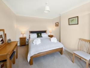 Un dormitorio con una cama con un escritorio y una silla. en Kilquhanity Cottage, en Castle Douglas