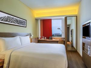 a bedroom with a large white bed and a window at ibis Chennai Sipcot - An Accor Brand in Chennai +62 photos
