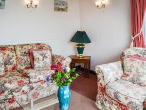 a living room with a couch and a vase with flowers at Sunny Bank - Uk34711 in Reighton