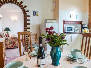 a table with a blue vase with flowers on it at Sunny Bank - Uk34711 in Reighton