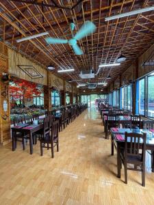 een eetkamer met tafels, stoelen en ramen bij Bình An Mountain Side Bungalow in Nguyên Ngoại