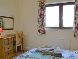 a bedroom with a bed and a desk and a window at Carribber Beech in Torphichen