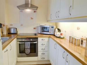 Una cocina con gabinetes blancos, estufa y microondas. en Cutcliffe Chambers - Hppr, en Bideford