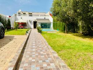 una casa con una pasarela de ladrillo delante de un patio en Belle villa spacieuse et calme avec piscine à 7min de la plage en voiture, en Tamaris